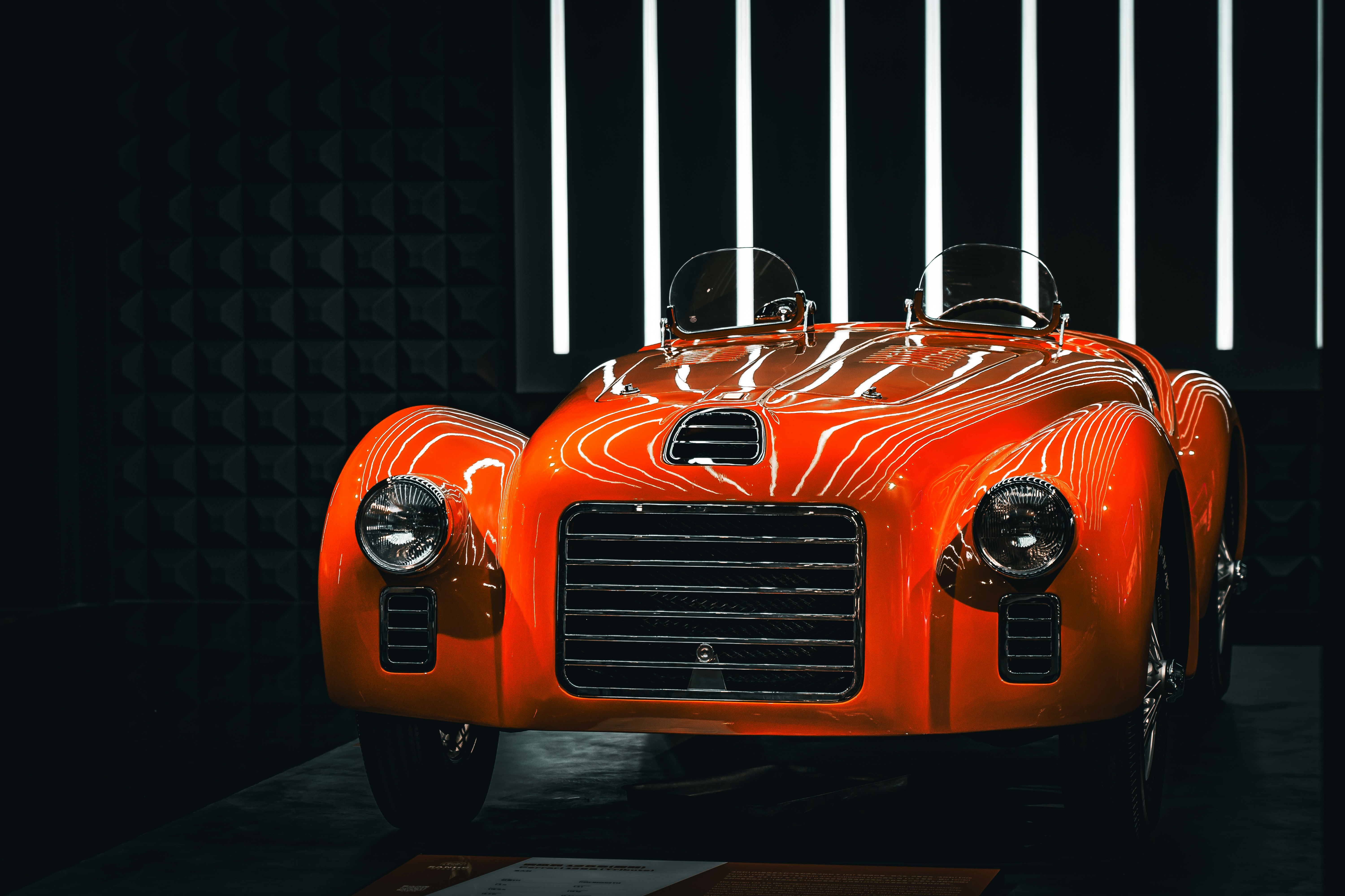 A shiny, orange classic car on display.