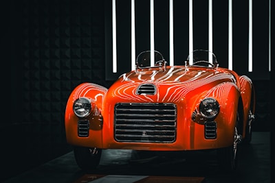 A shiny, orange classic car on display.