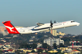 A qantas plane takes off over a cityscape.