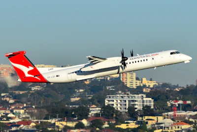 A qantas plane takes off over a cityscape.