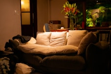 A cozy living room with couch, flowers, and light.