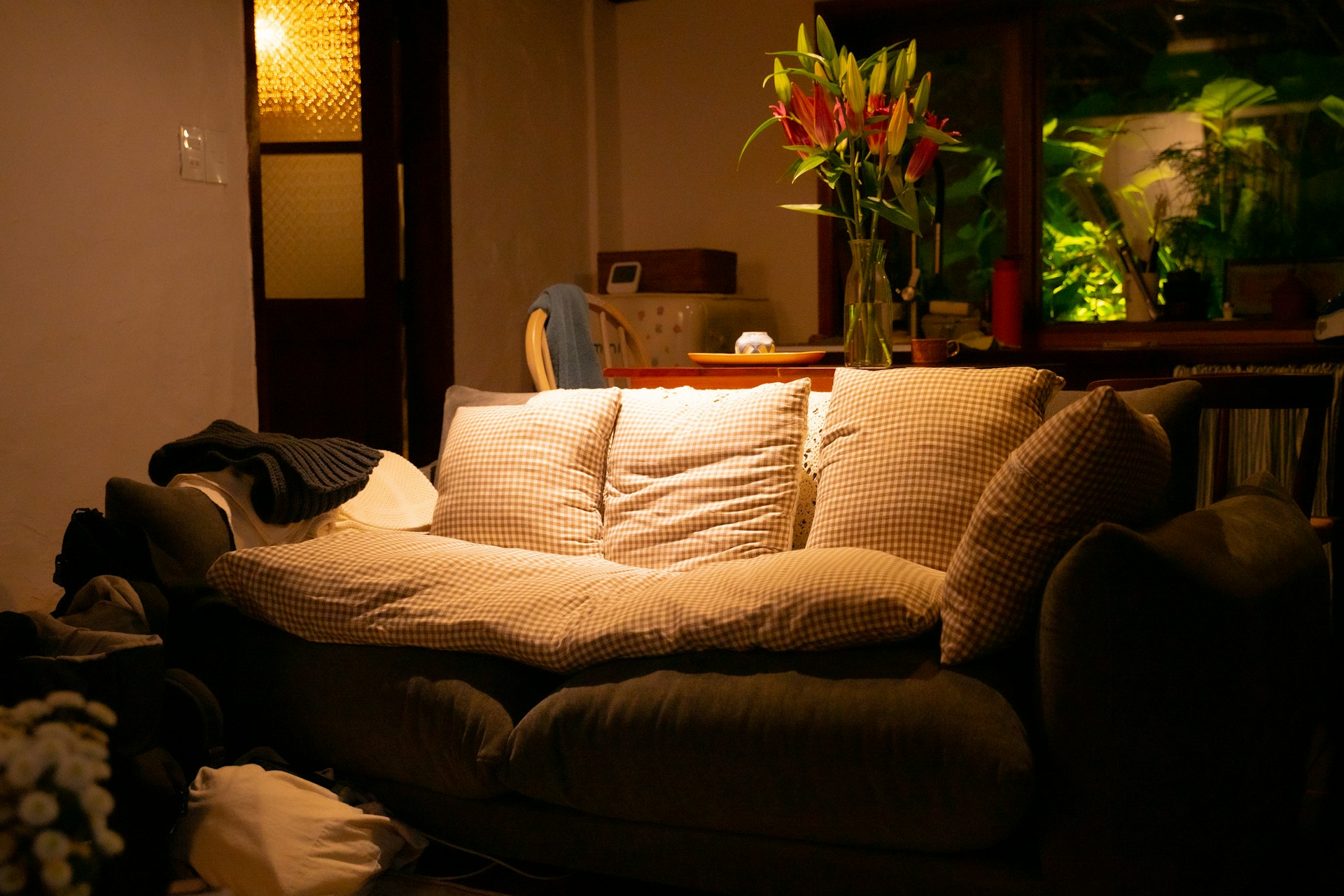 A cozy living room with couch, flowers, and light.