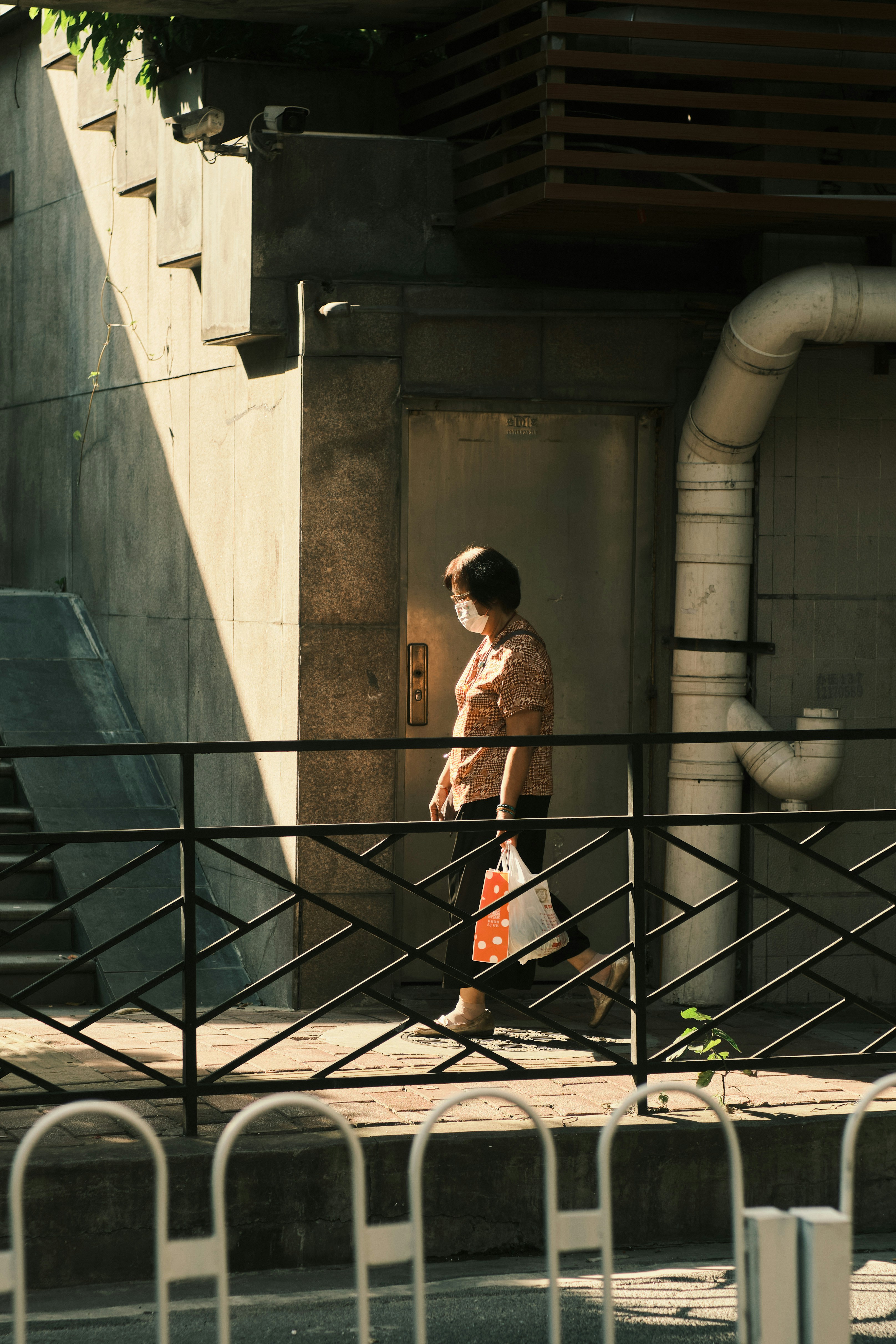 Woman walks on the sidewalk, wearing a mask.