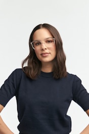 A woman wears glasses and a navy sweater.