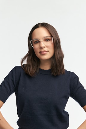 A woman wears glasses and a navy sweater.