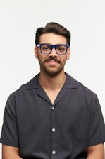 A man with blue glasses smiles at the camera.