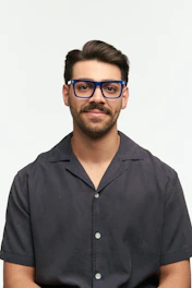 A man with blue glasses smiles at the camera.