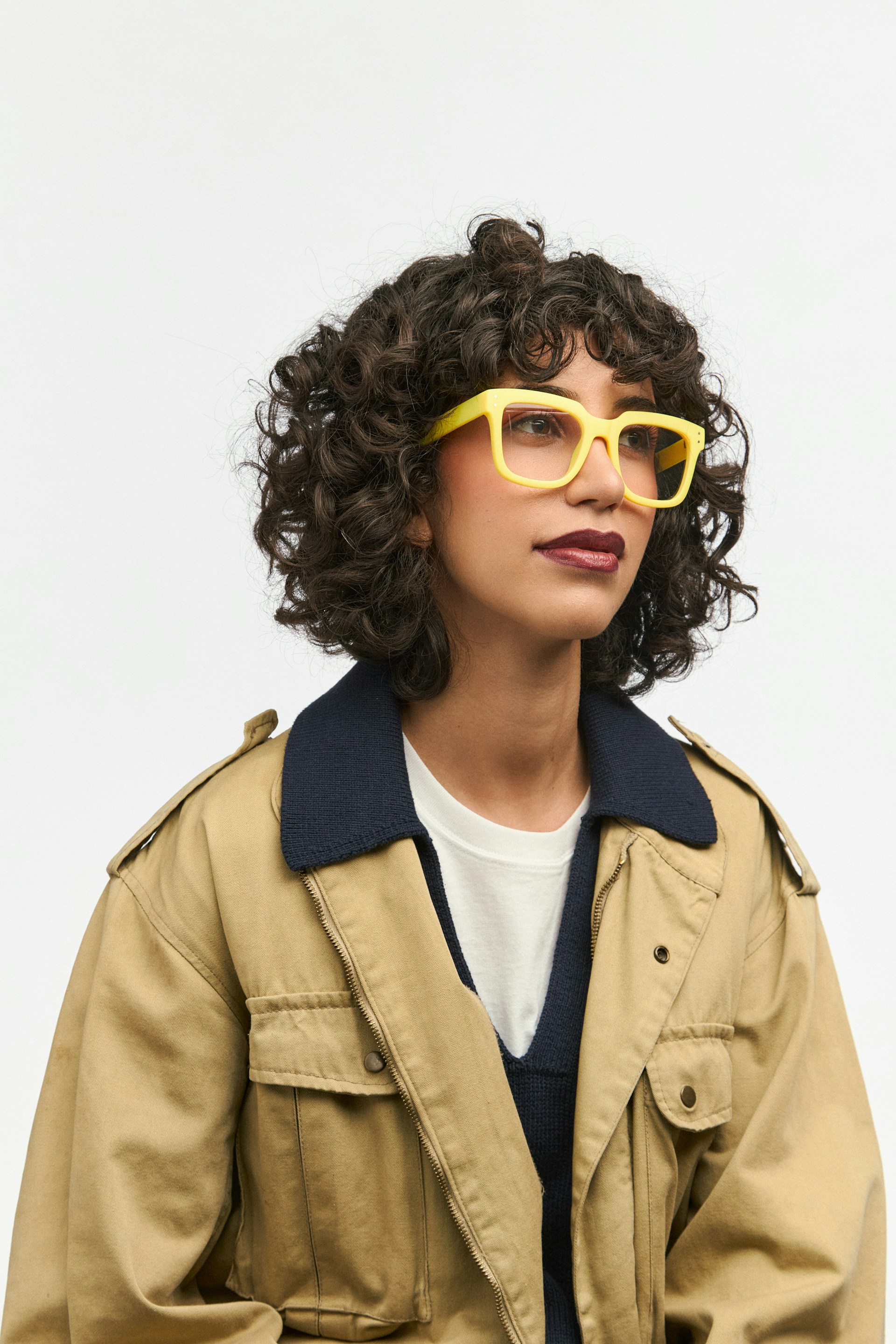 Woman with yellow glasses and a tan coat.