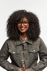 A smiling woman with curly hair wears glasses.