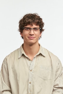 A young man wearing glasses poses for a portrait.