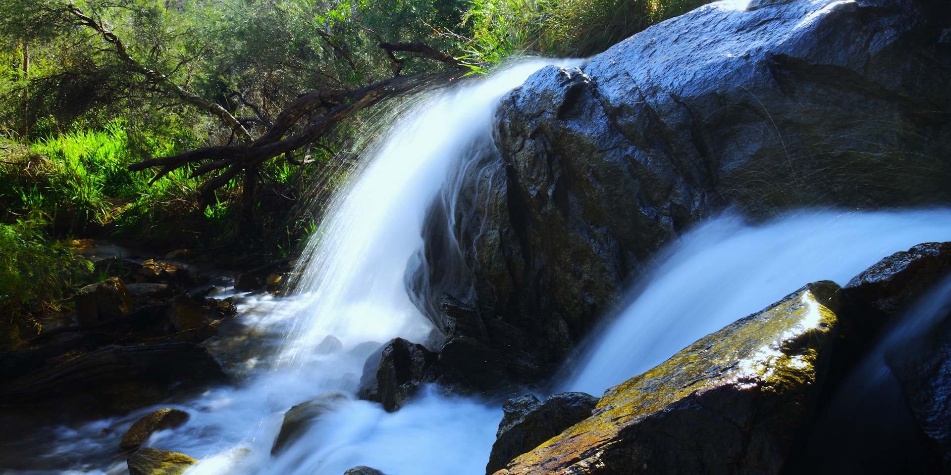 A cascading waterfall rushes over rocks and boulders.