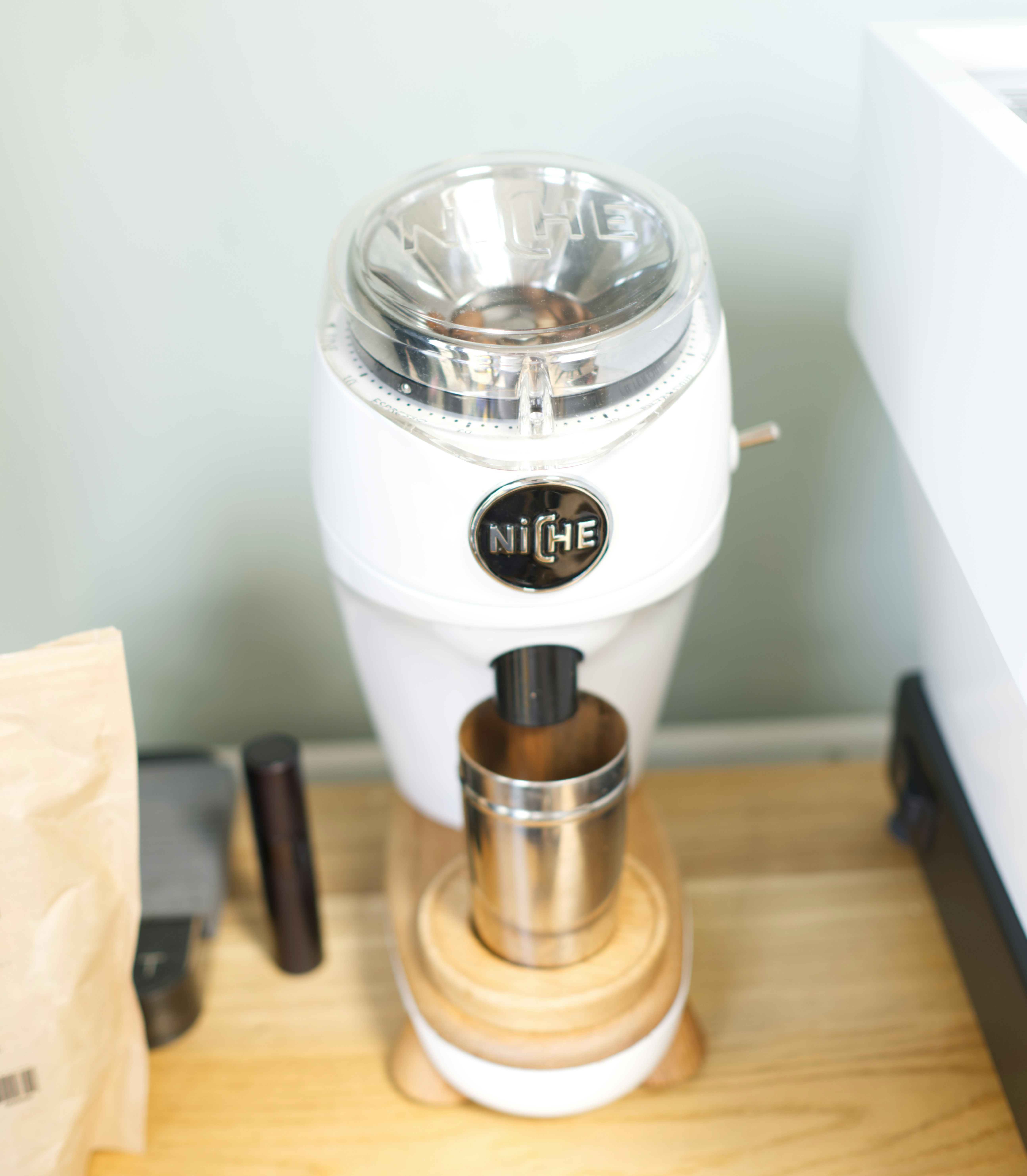 A white coffee grinder stands ready to use.