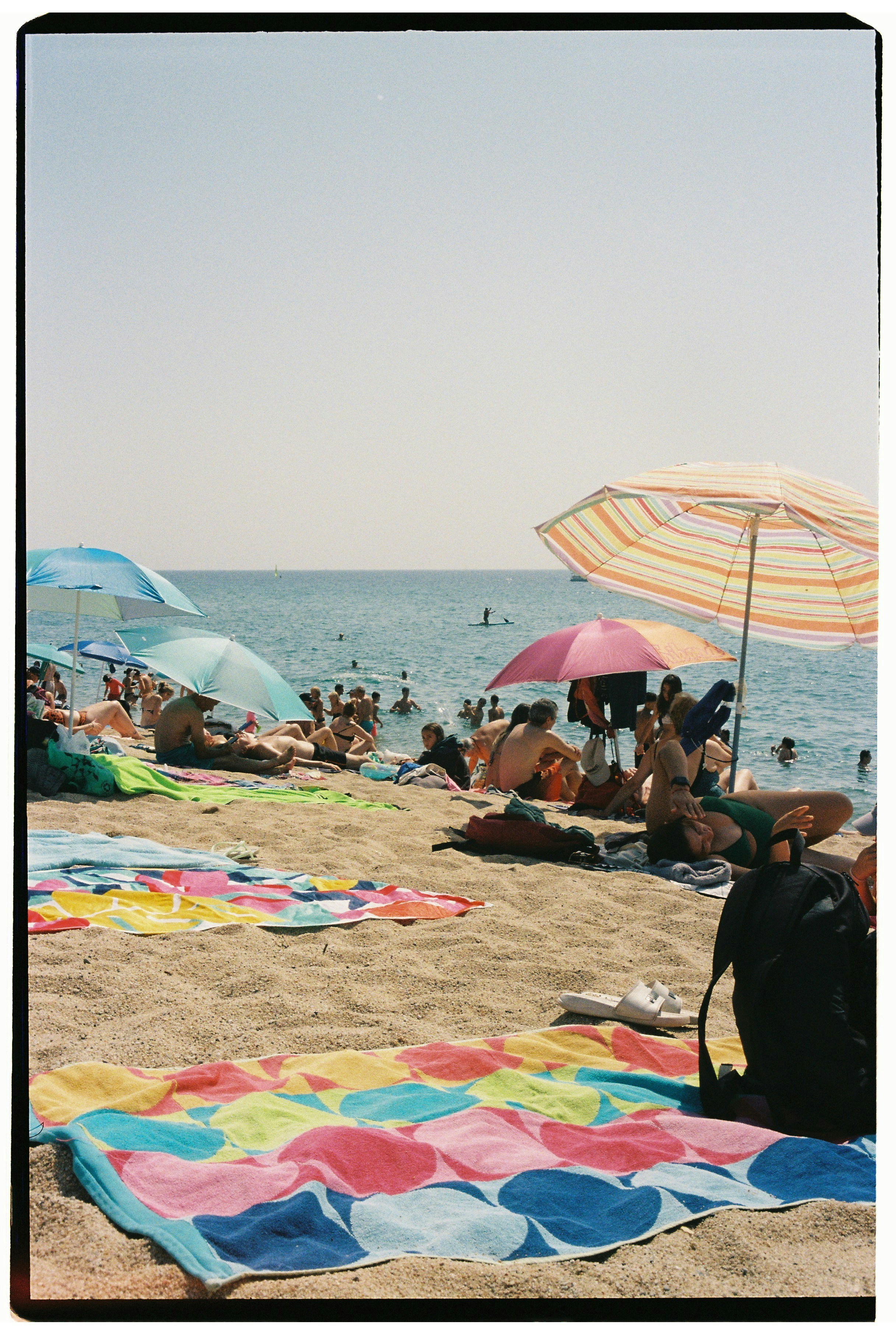 People enjoy a sunny day at a crowded beach.