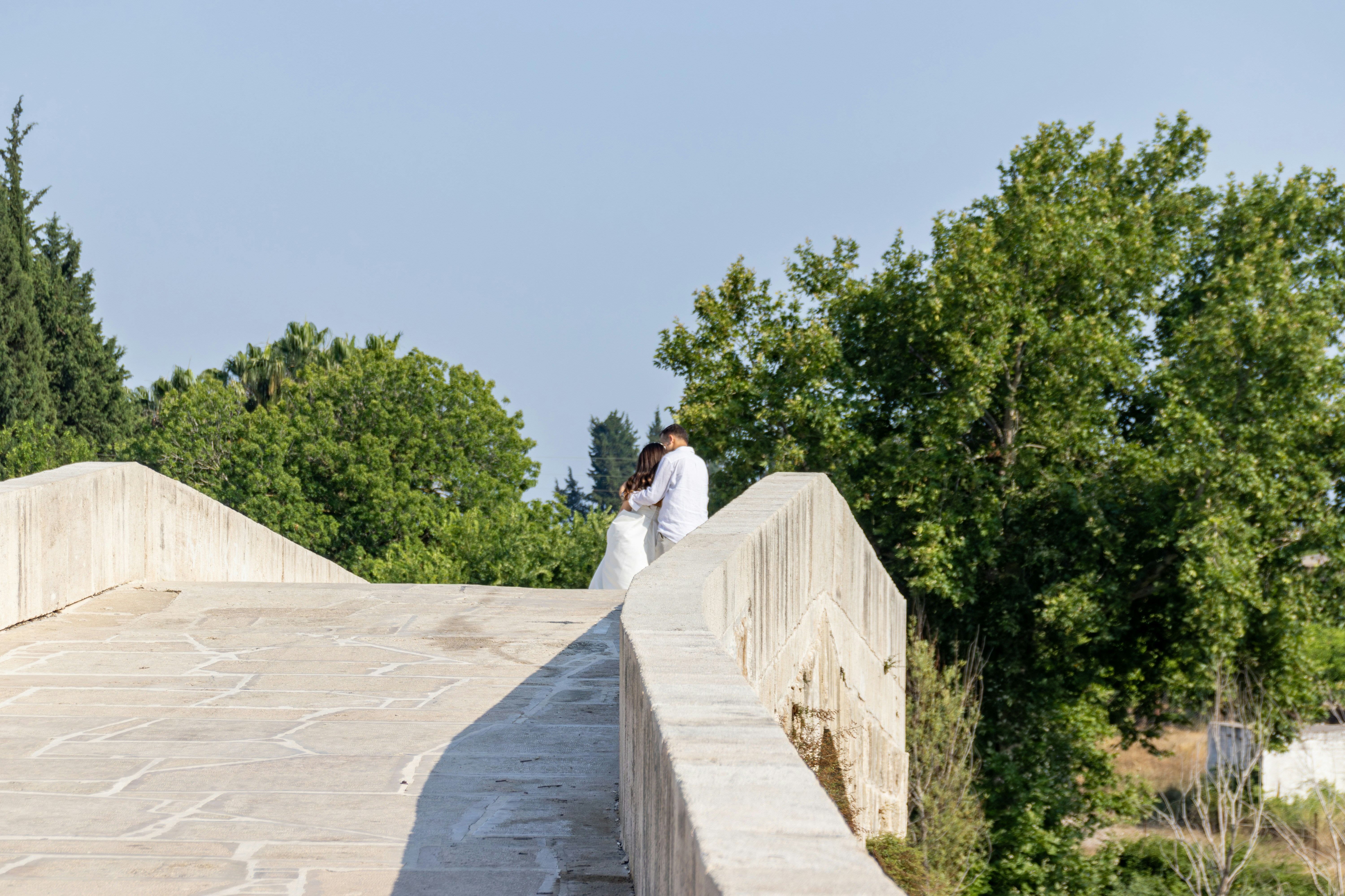 Ein frisch vermähltes Paar umarmt sich auf einer Steinbrücke.