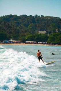 Surfer rides a wave in front of a beach.