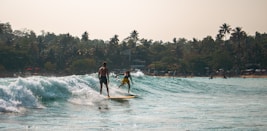 Two surfers ride the wave in the ocean.