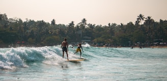 Two surfers ride the wave in the ocean.