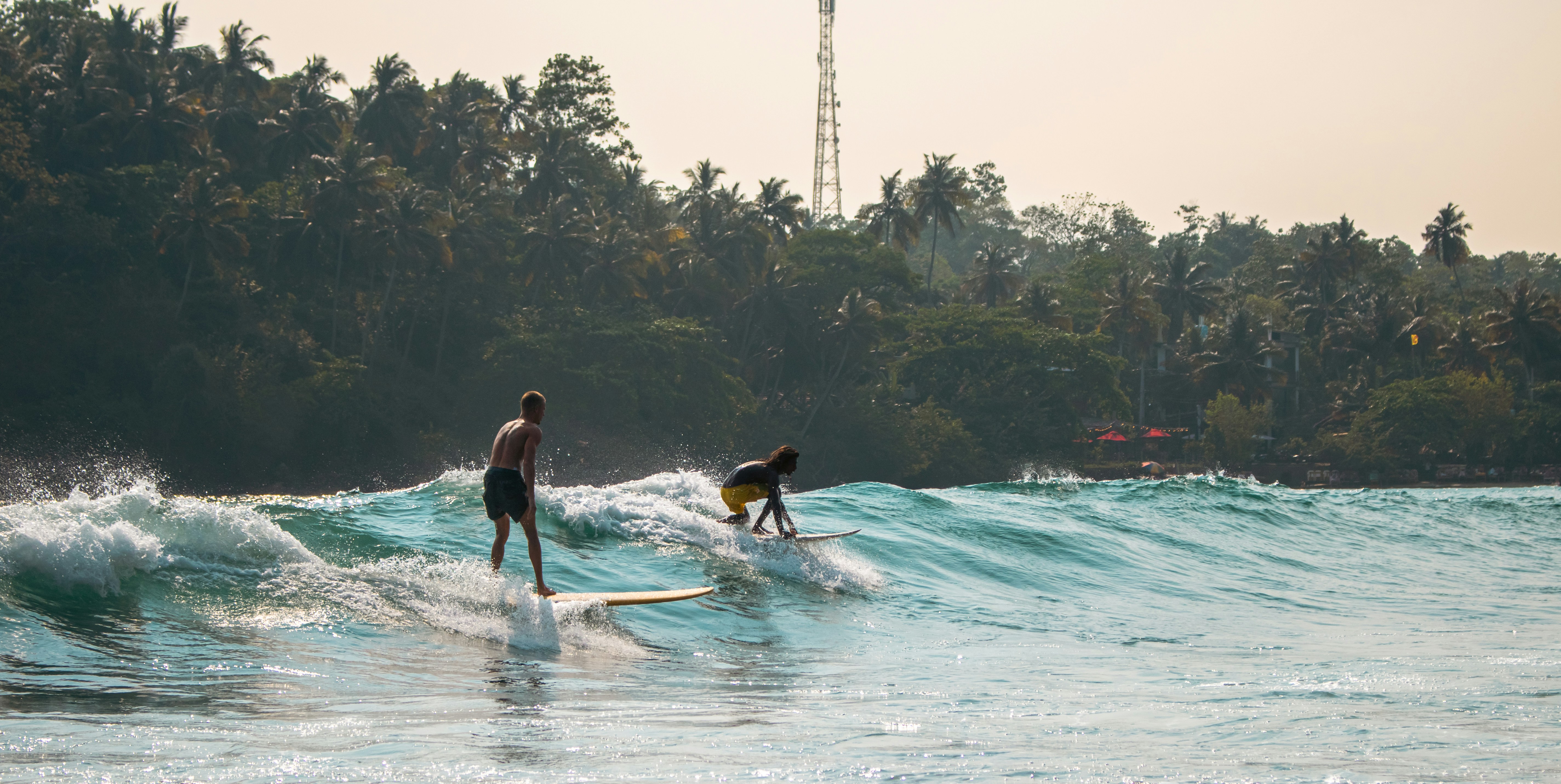 Surfers ride waves in ocean water.
