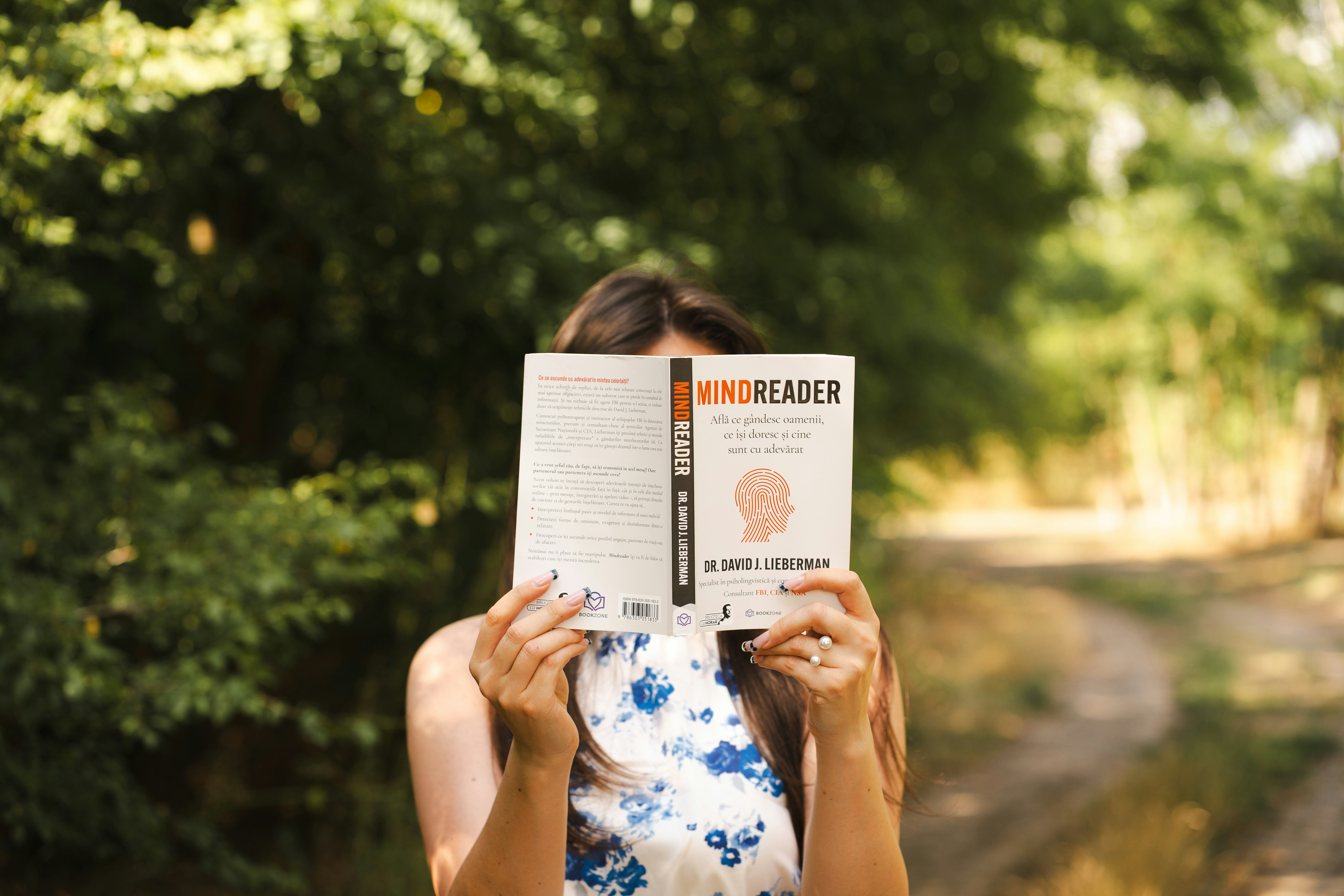 Una mujer lee un libro al aire libre.