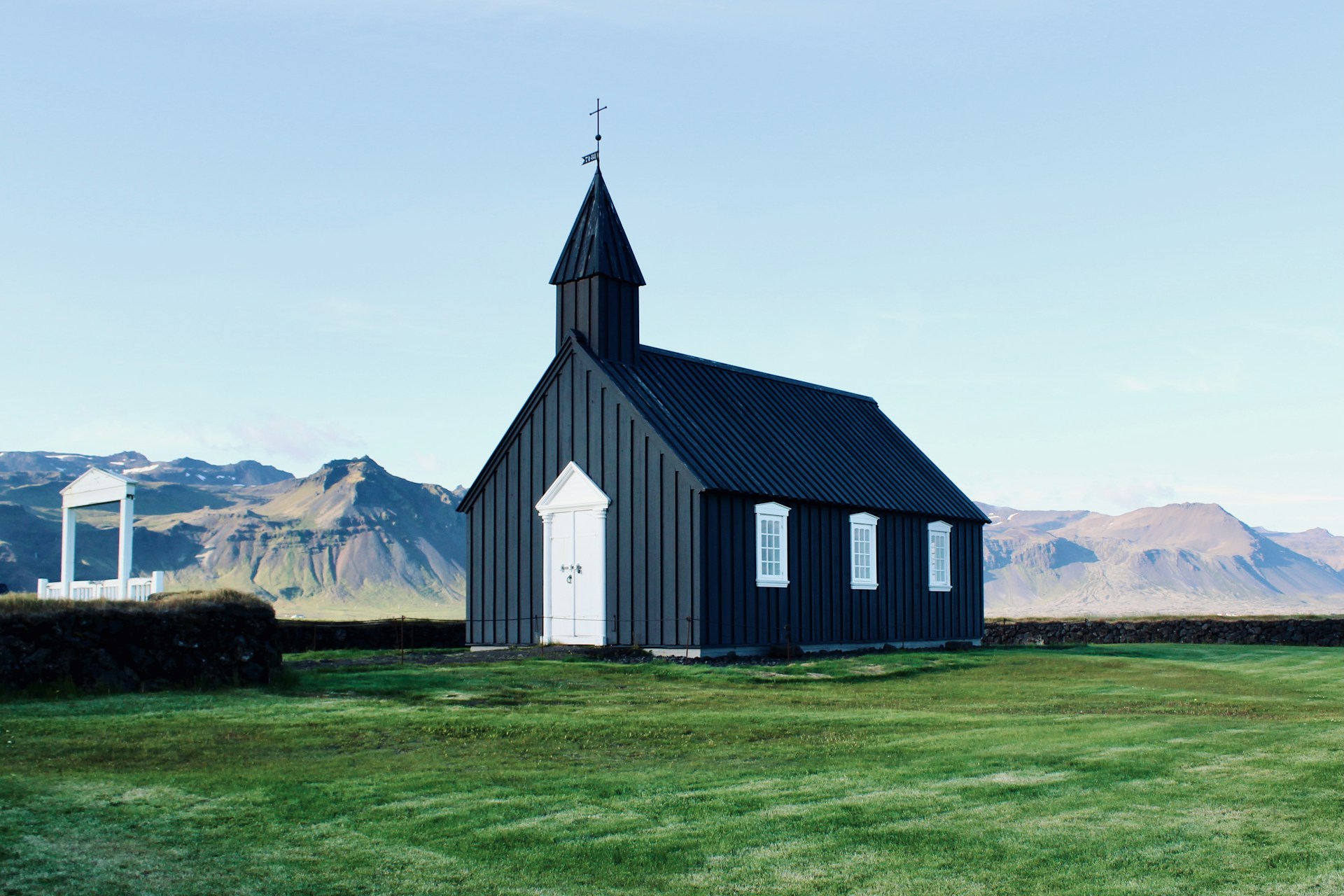 A black church stands in a field.
