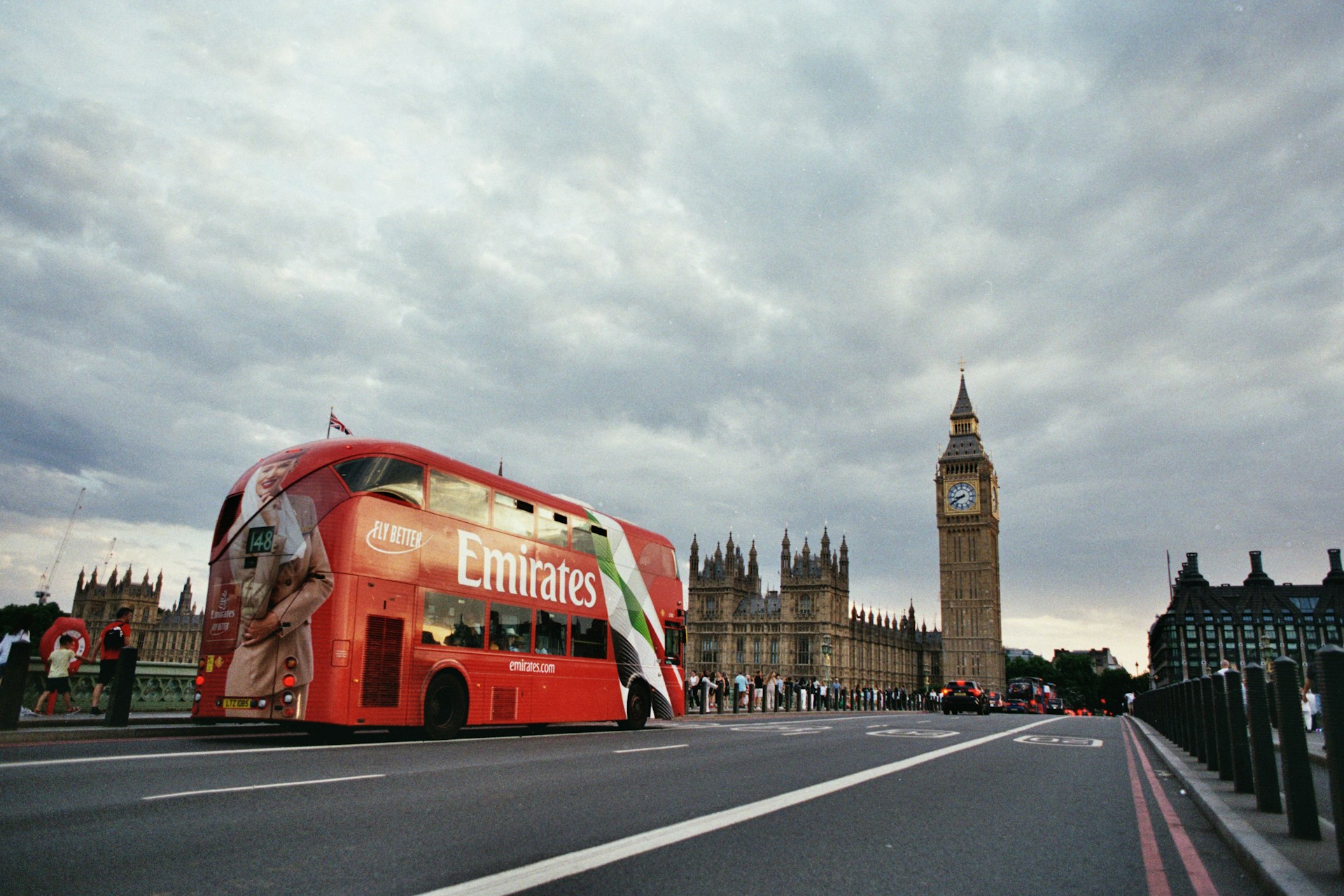 A red bus passes big ben in london.