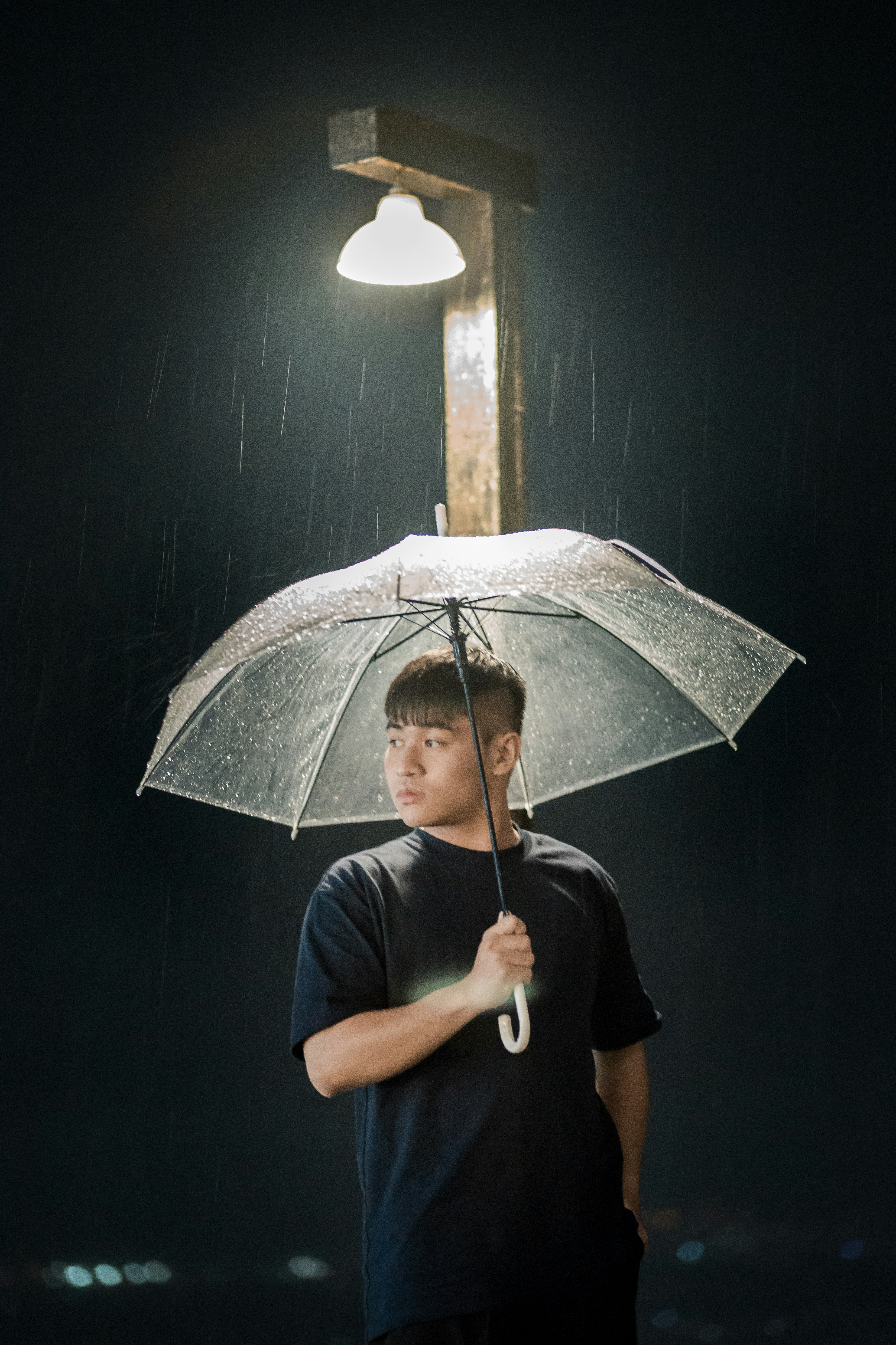 Man stands in the rain under an umbrella.