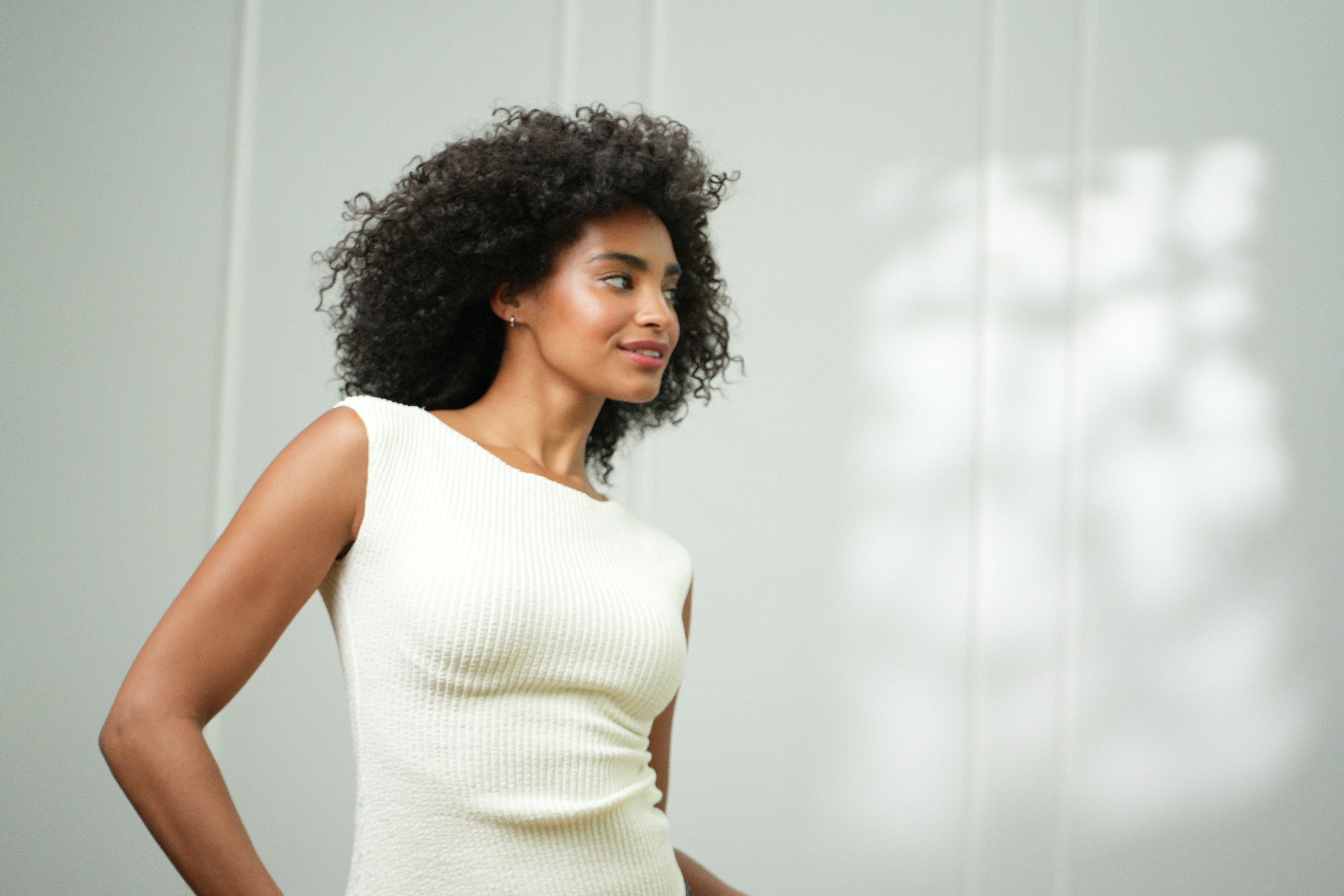 A woman smiles, posing in a white dress