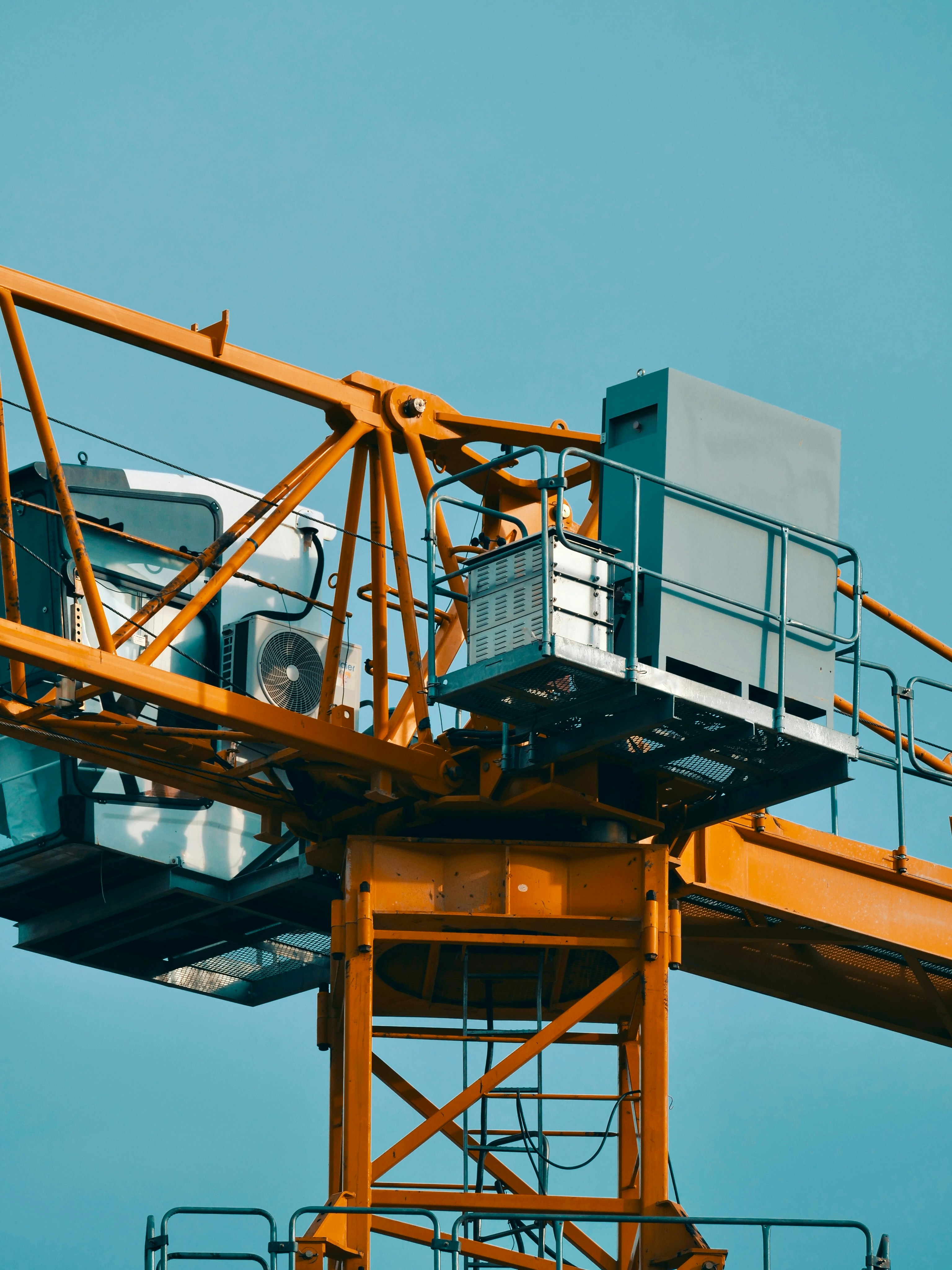 A construction crane stands against a blue sky.