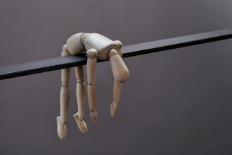 Mannequin doll hangs limply from a dark beam.