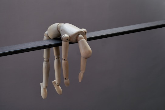 Mannequin doll hangs limply from a dark beam.