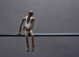 A wooden mannequin sits sadly with a bandage.