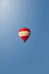 A red and white hot air balloon soars in the sky.