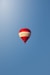 A red and white hot air balloon soars in the sky.
