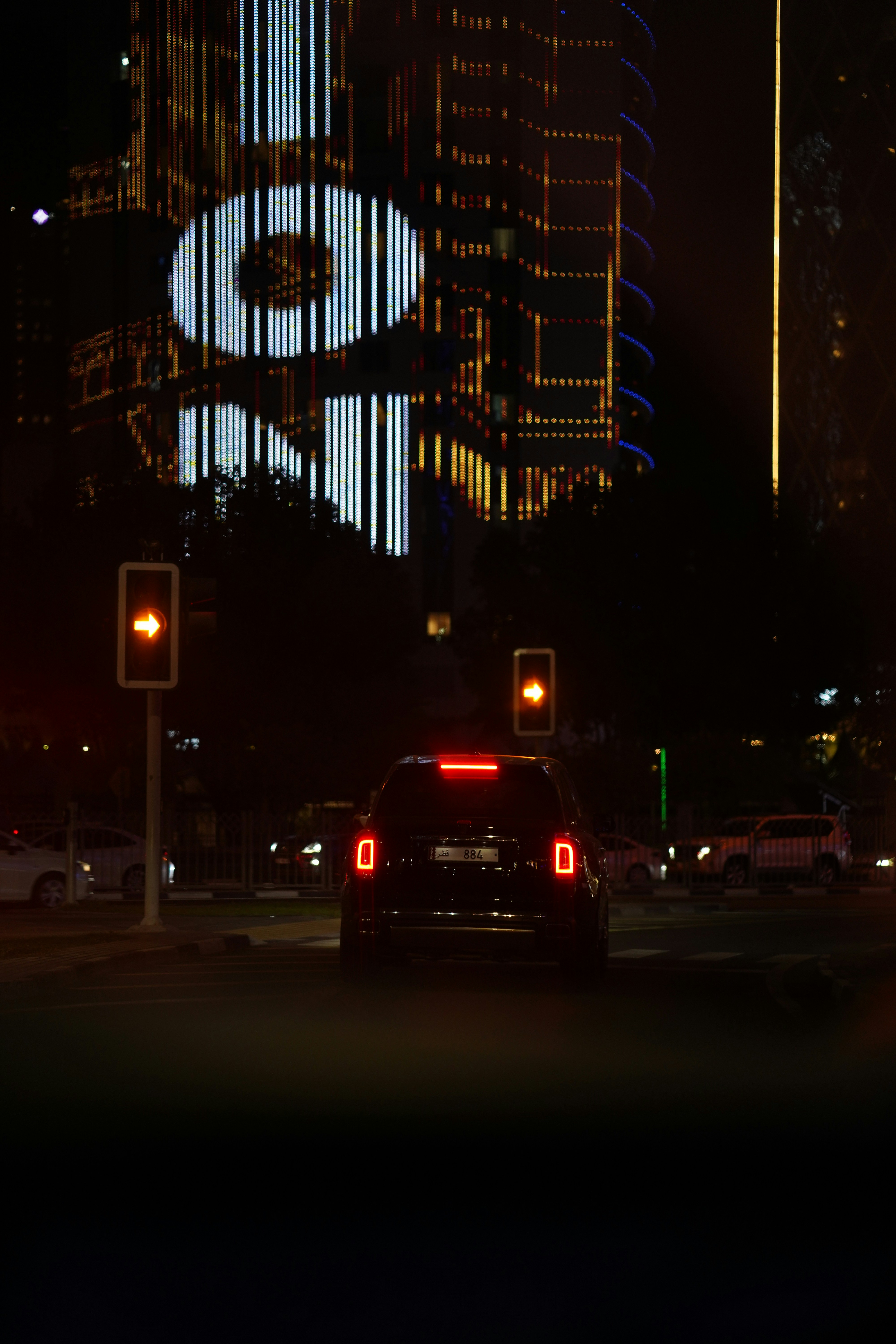 A car drives in front of a lit skyscraper