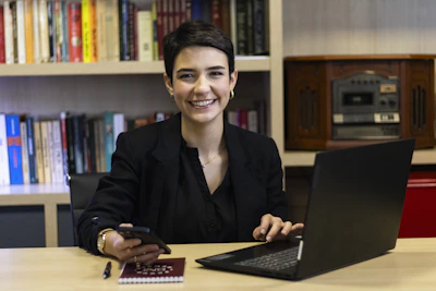 A woman smiles while working on a laptop.