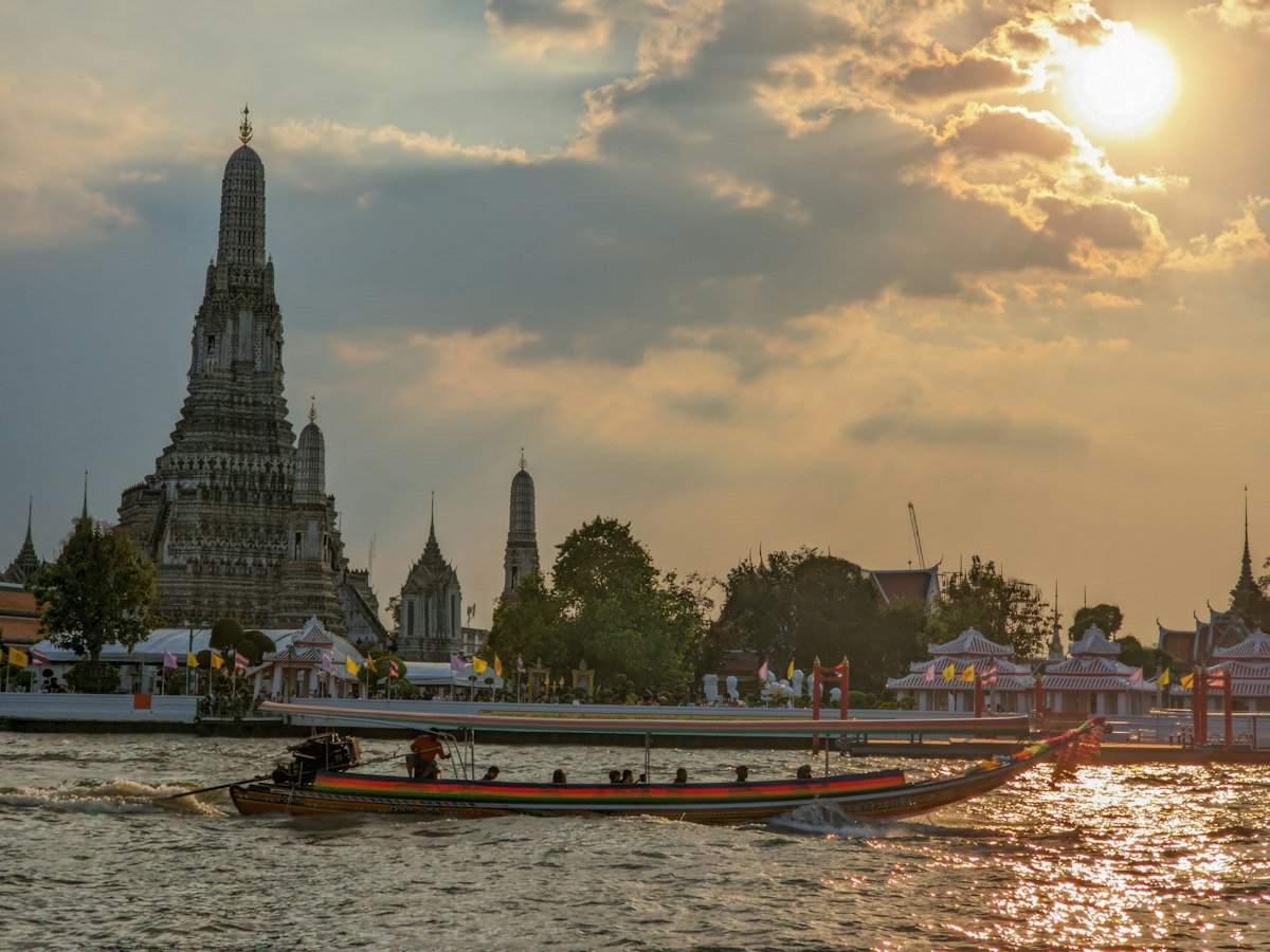 Bateau sur le Chao Phraya devant le Wat Arun au coucher du soleil, Bangkok