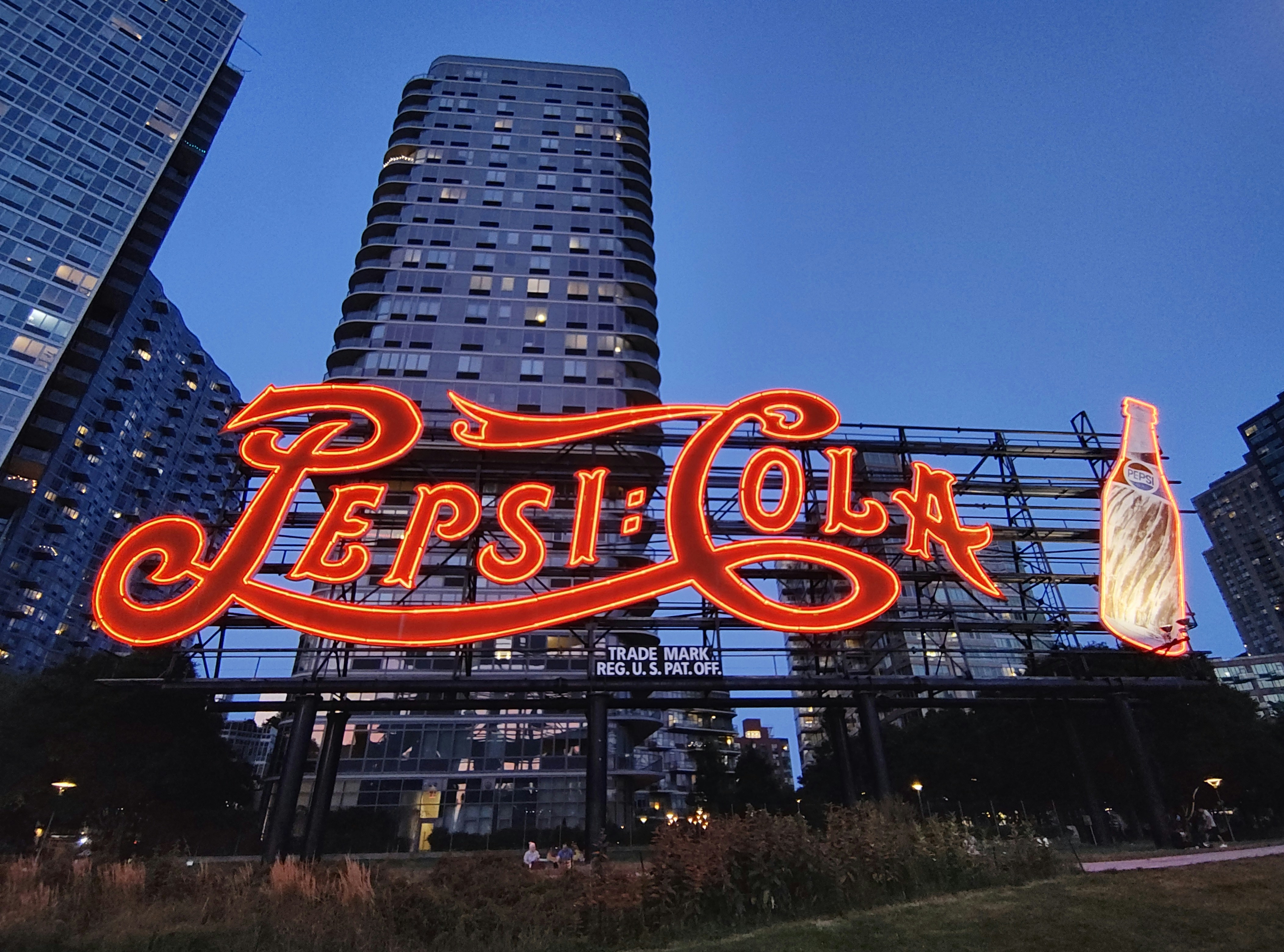 The pepsi-cola sign lights up at dusk.