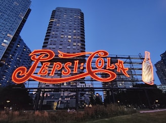 The pepsi-cola sign lights up at dusk.