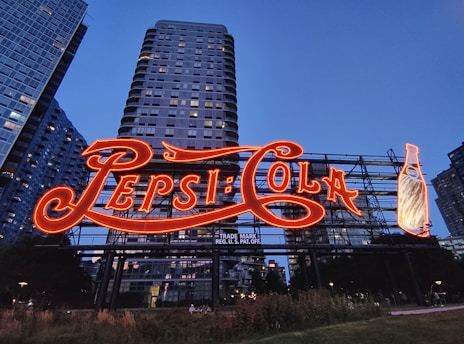 The pepsi-cola sign lights up at dusk.