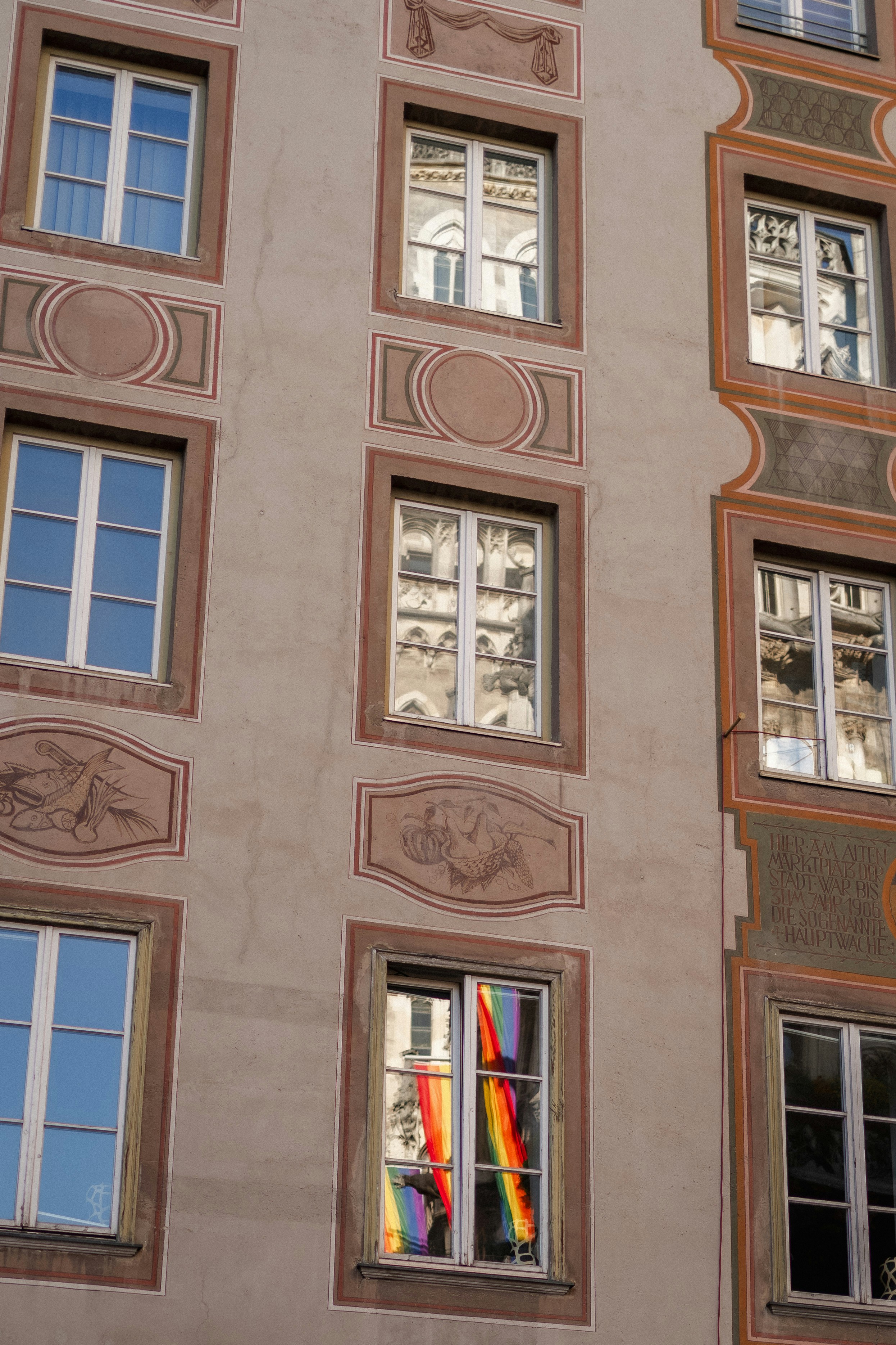 A rainbow flag reflects in the building's window.
