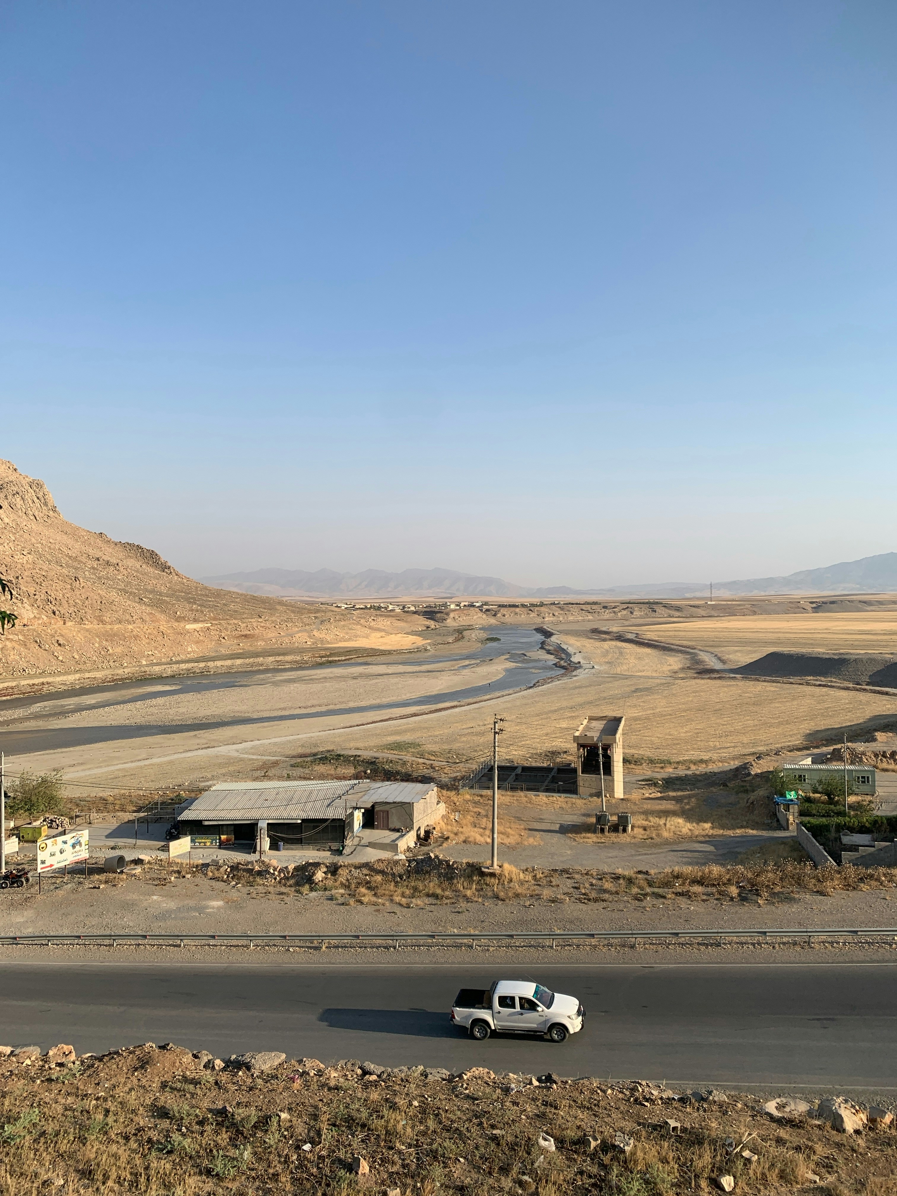 A white truck drives along a desert road.