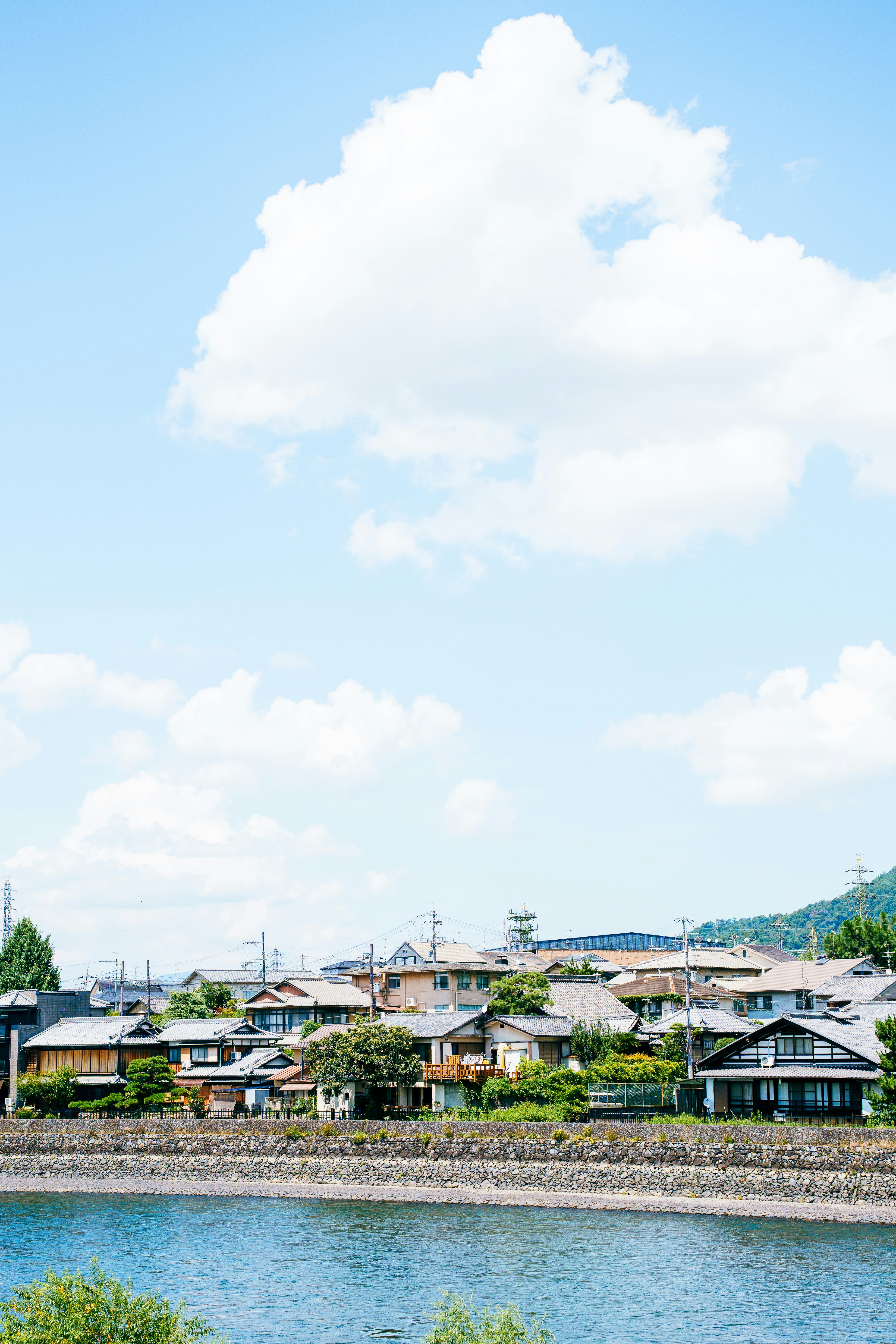 曇り空の下、川沿いに家々が建っています。の写真 – Unsplashの旅行の無料画像