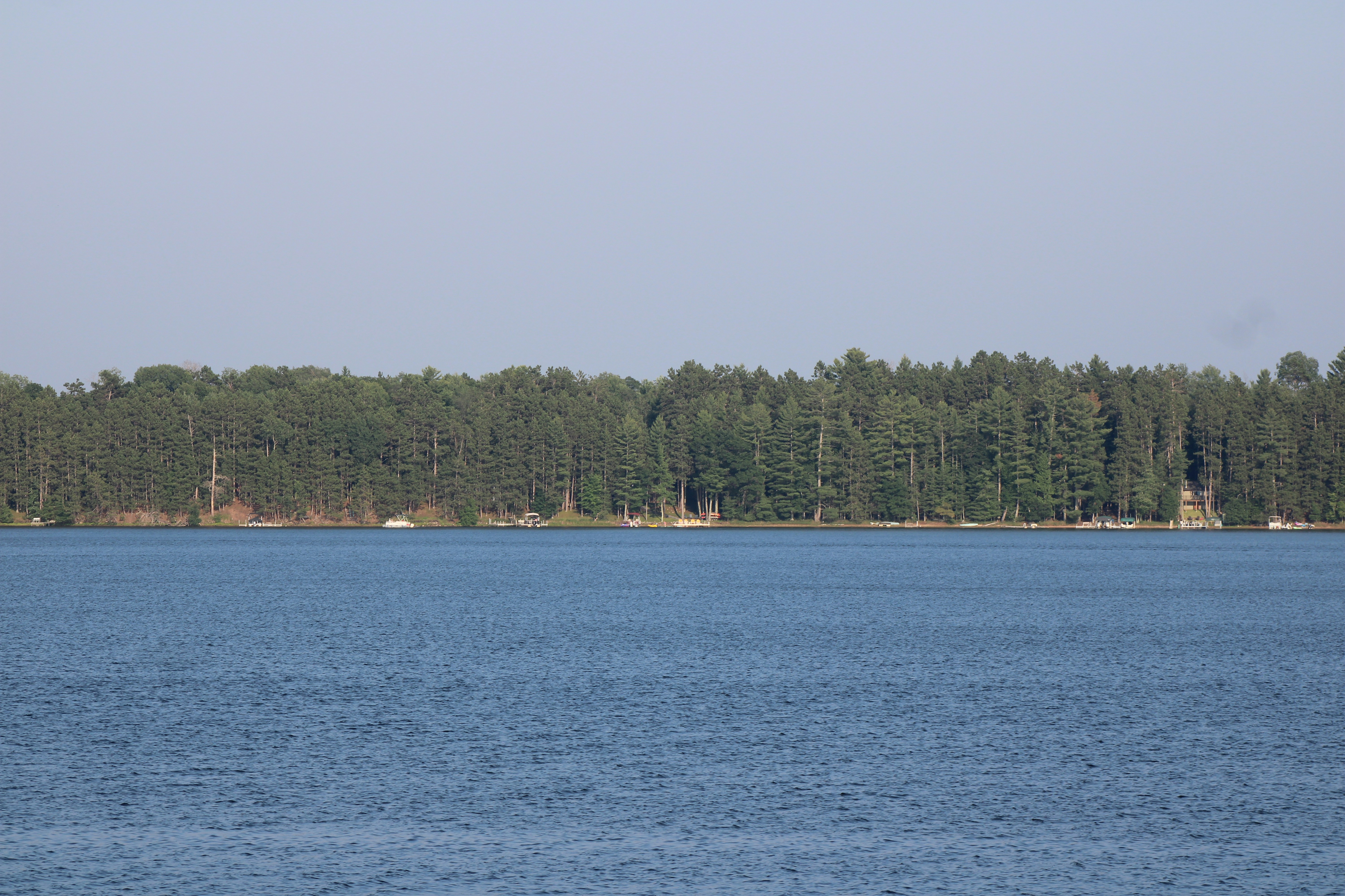 A calm lake reflects a forest shoreline.