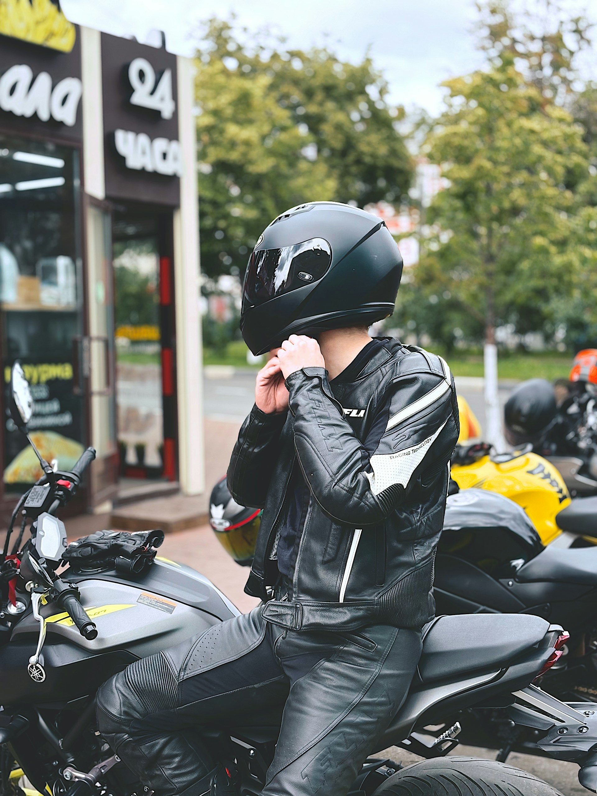 A rider adjusts their helmet before riding a motorcycle.