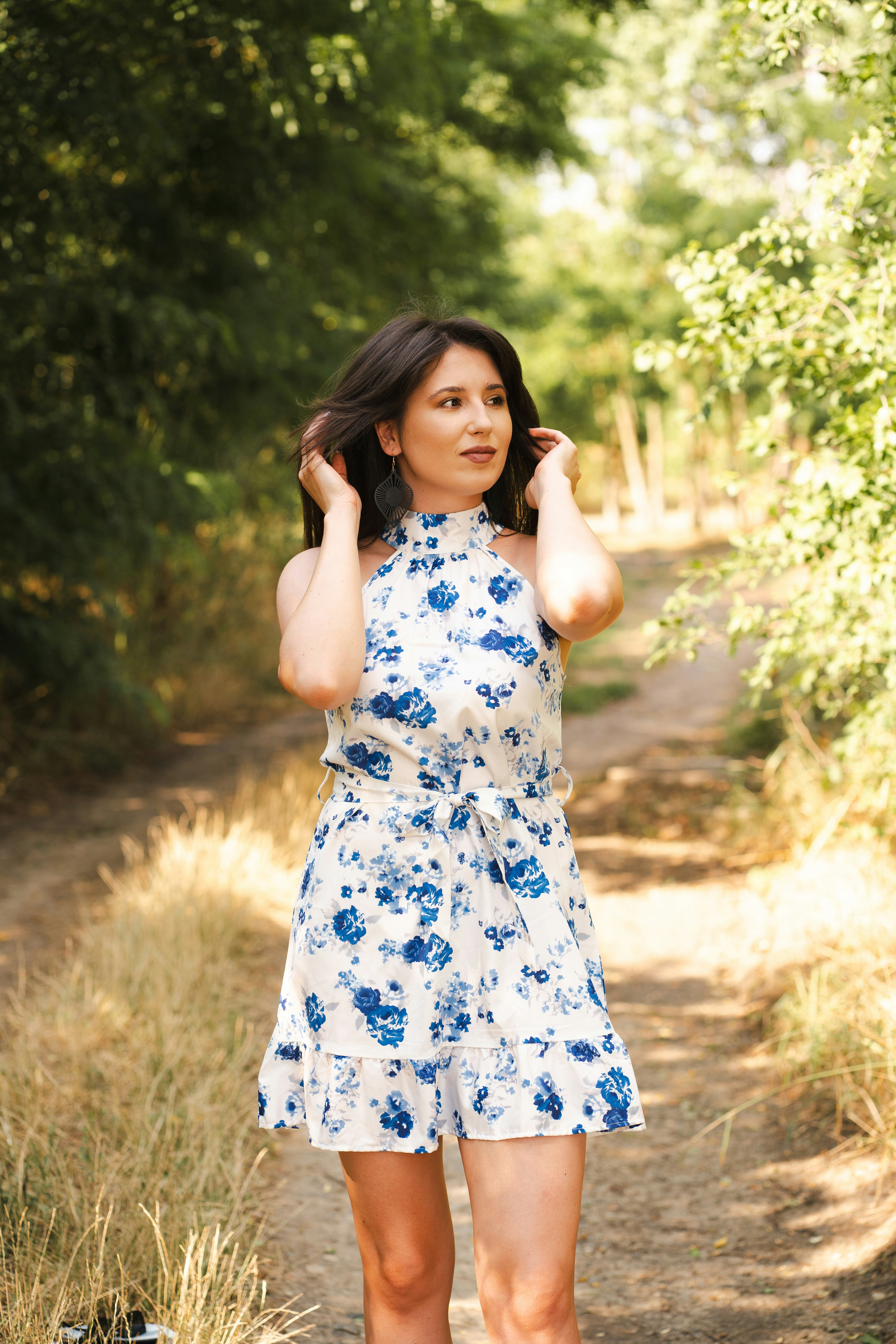 Una mujer posa en un camino en el bosque.