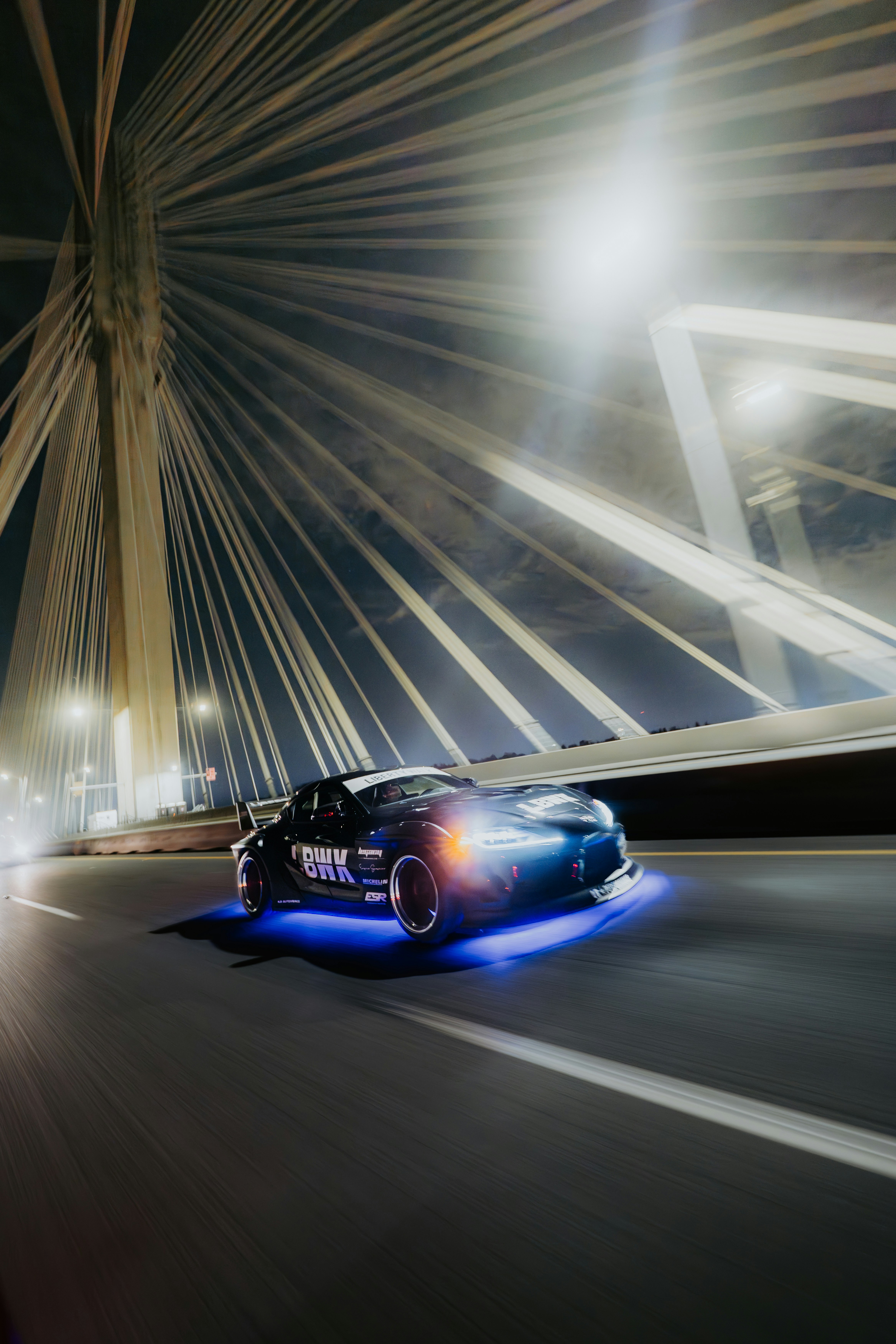 A sports car drifts under a lit-up bridge. photo – Free Image on Unsplash