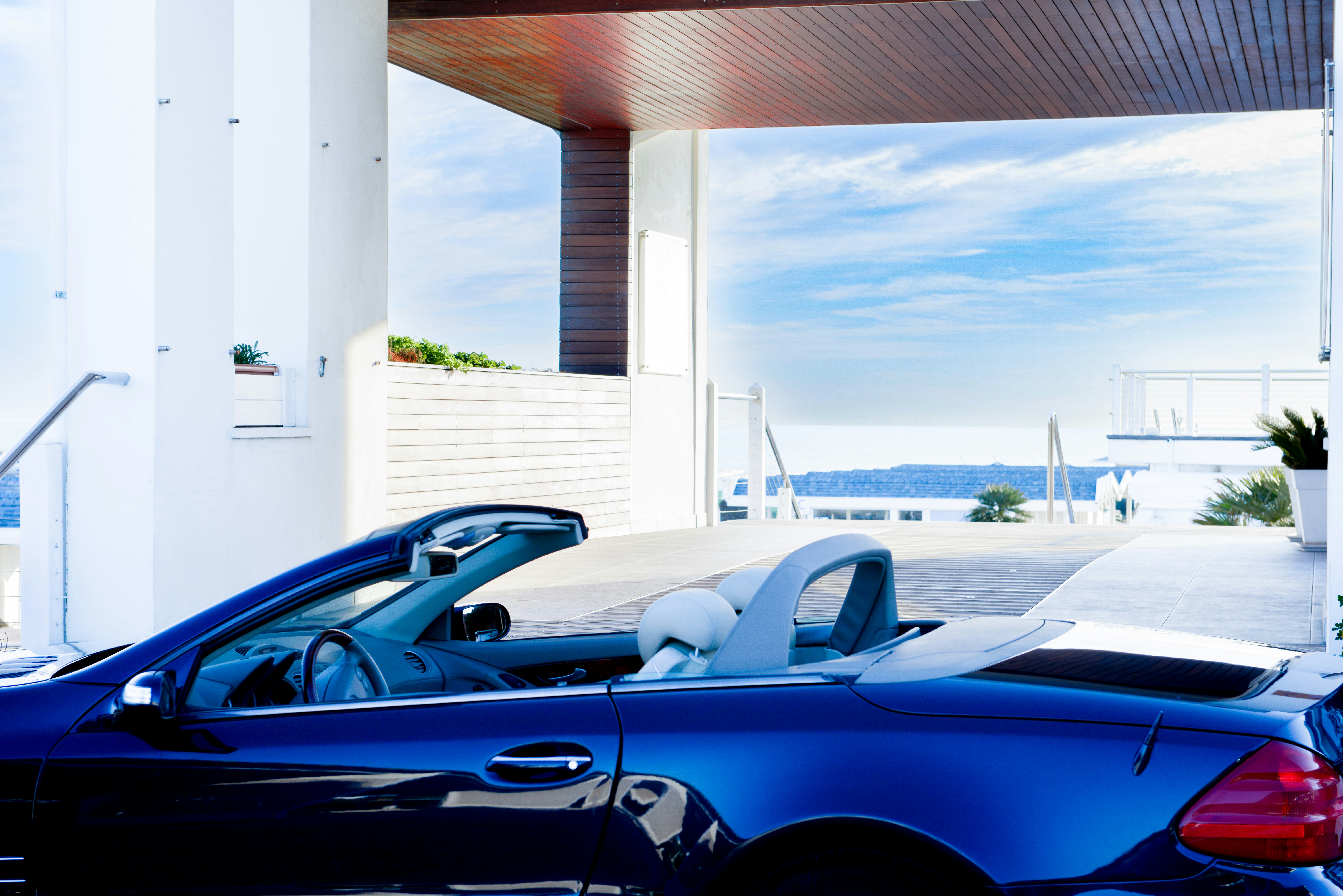 A blue convertible is parked near the ocean.