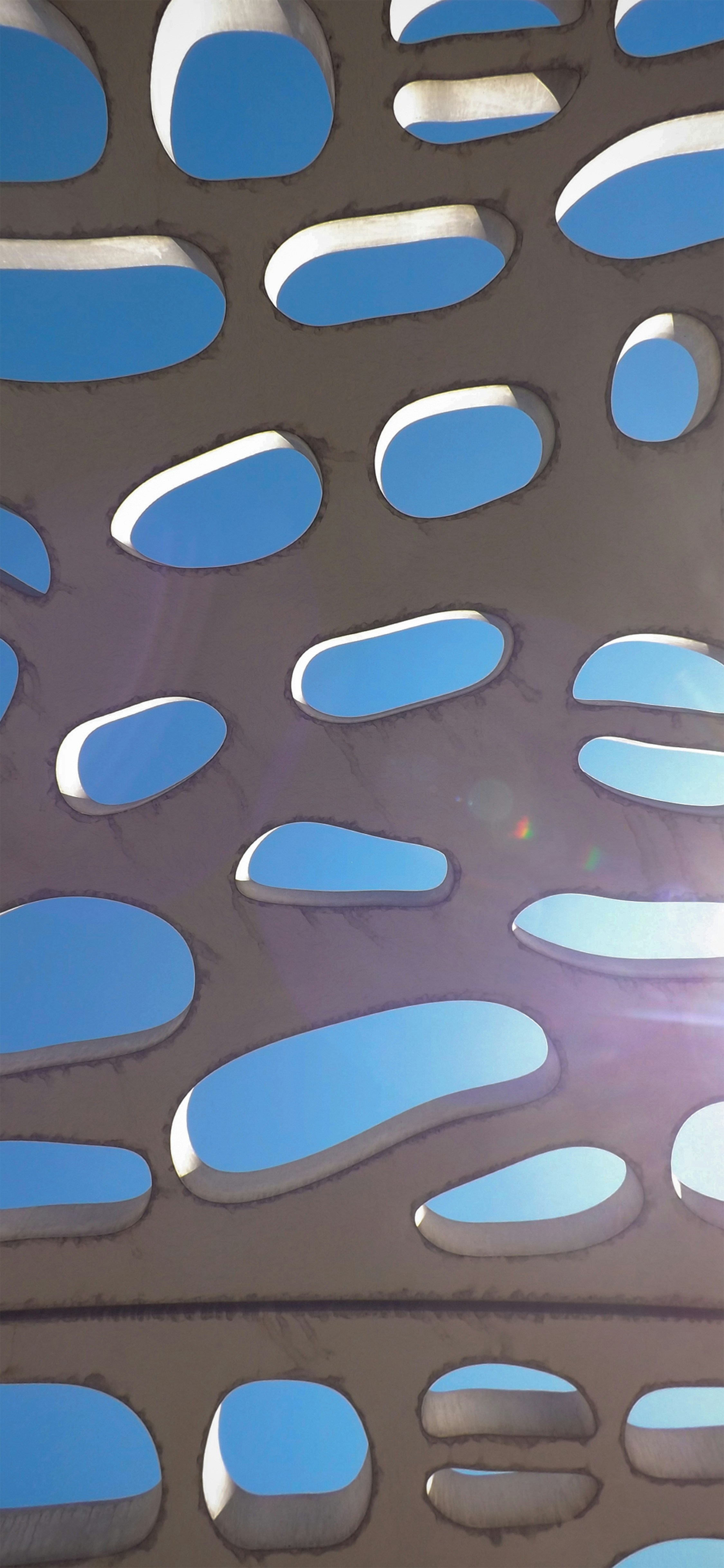 A wall with holes reveals the sky.