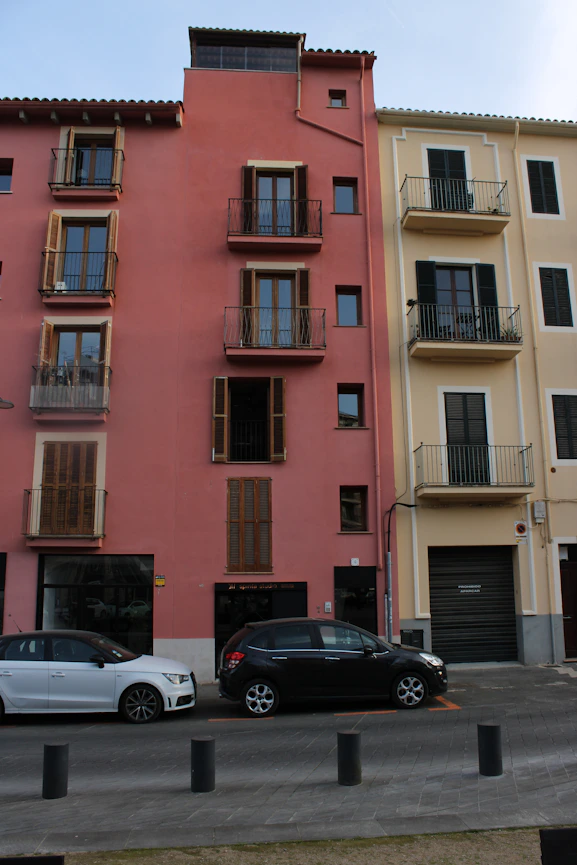 Colorful buildings stand next to parked cars on the street