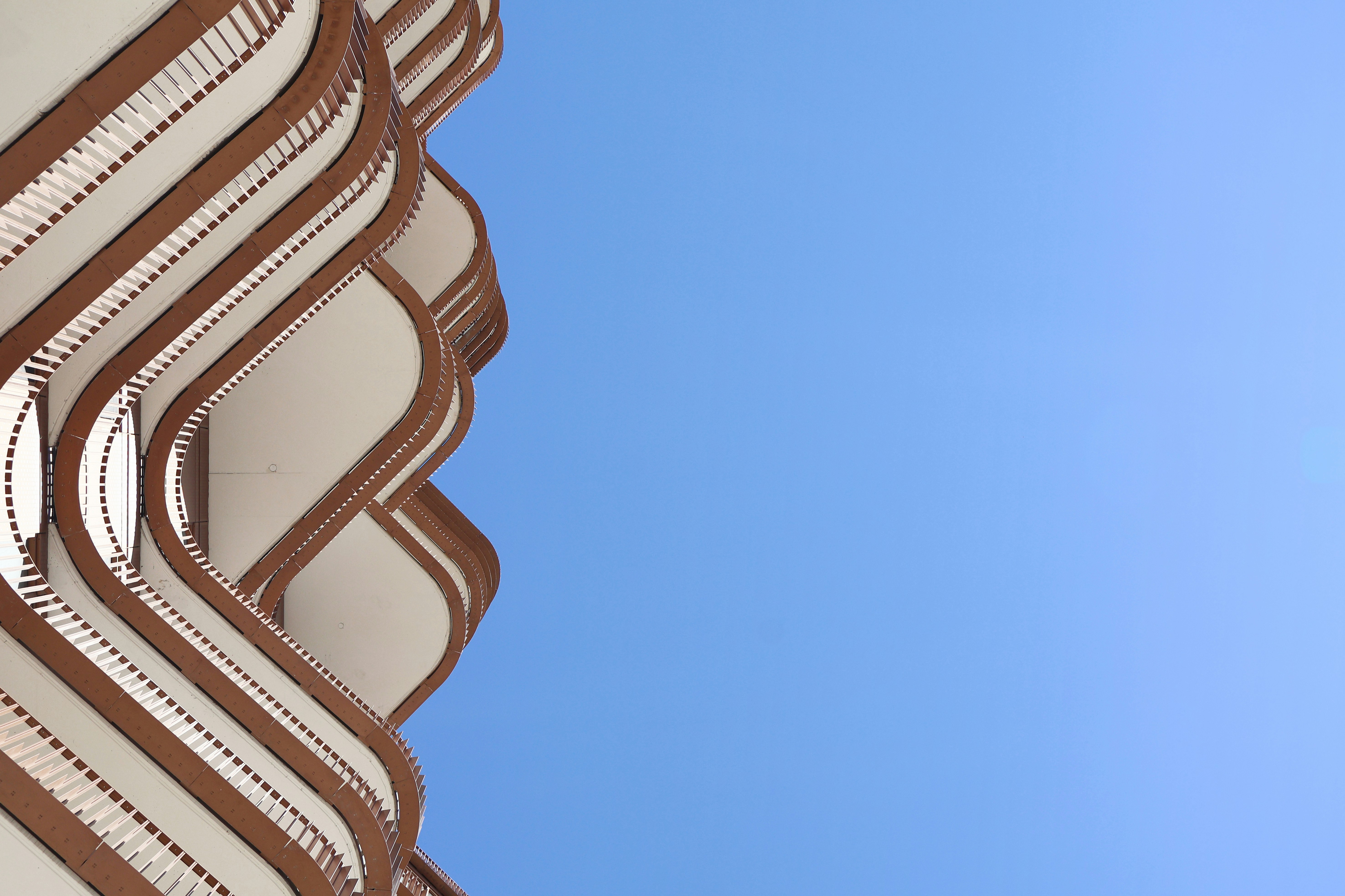 Balconies of a building against a bright blue sky.